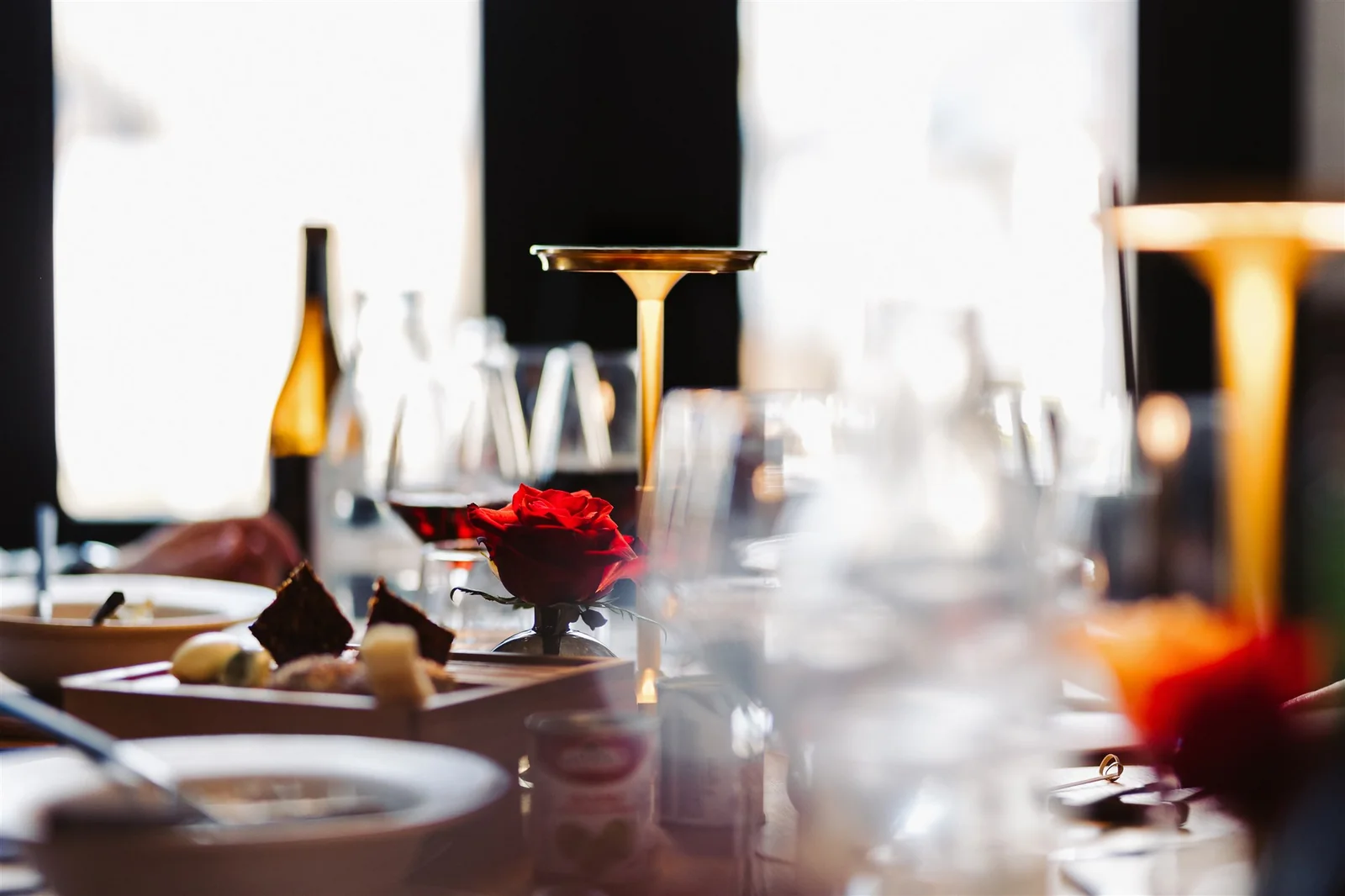 A red rose, wine glasses and warm lamps at a set table at Kalcium